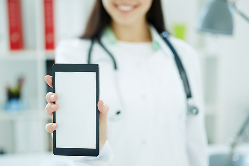 Smartphone con espacio para texto o imagen en la mano de la doctora. Concepto de publicidad médica. Foto con profundidad de campo photo