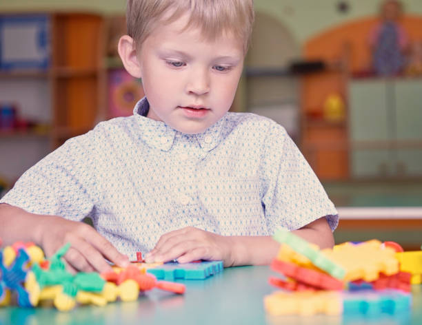 istock Little cute boy plays with constructor next to the mountains of colored details 876784140