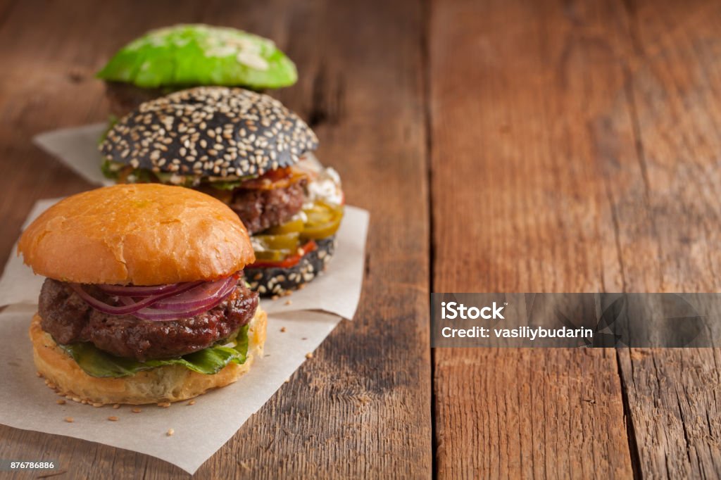 Set of three mini homemade Burger with marble beef and vegetables on a old wooden background. the concept of junk food and fast food. with copy space Set of three mini homemade Burger with marble beef and vegetables on a old wooden background. the concept of junk food and fast food. with copy space. Barbecue - Meal Stock Photo