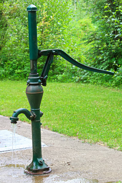 an old fashion hand pump pouring water - well fountain water pipe pipe imagens e fotografias de stock