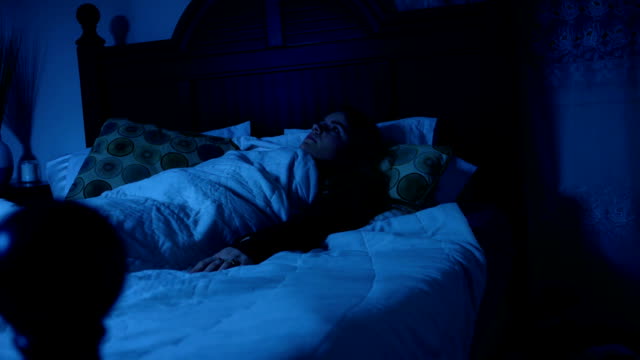 Woman suffering from sleep paralysis in bedroom at night