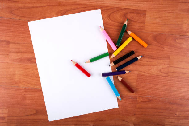 Colored pencil and white empty paper on wooden table stock photo