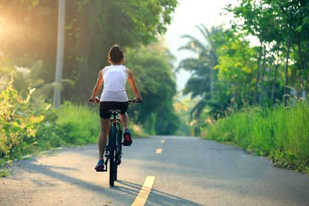 istock Young  woman cyclist cycling on tropical forest trail 876828634