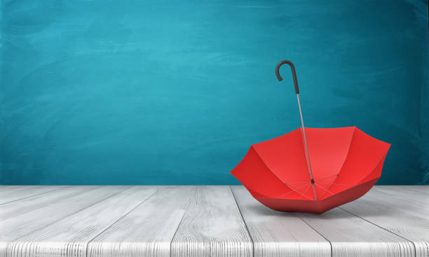 istock 3d rendering of a single red open umbrella lying on its side with an open canopy on a wooden surface on blue background. 876831750