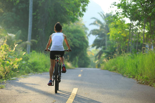 istock Young  woman cyclist cycling on tropical forest trail 876832068