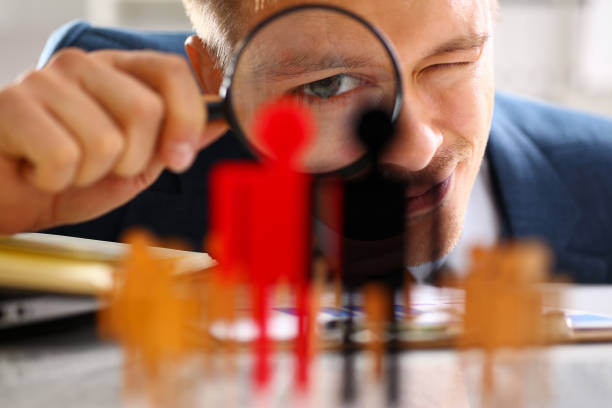 Man in suit look thru loupe on statuettes closeup