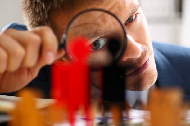 istock Man in suit look thru loupe on statuettes closeup 876838196