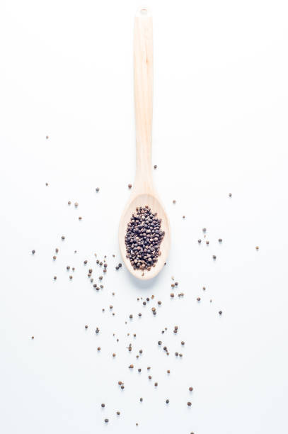 istock Black pepper in wooden spoon over white background 876844432