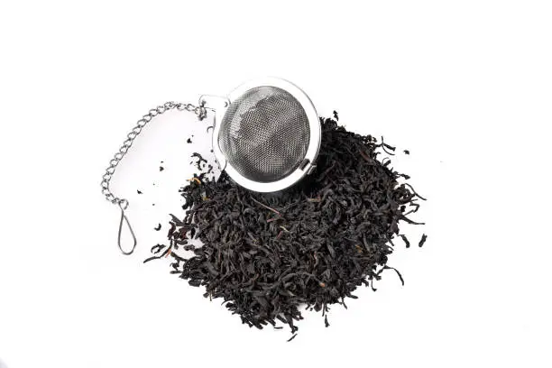 A ball tea infuser on a mound of whole leaf black tea