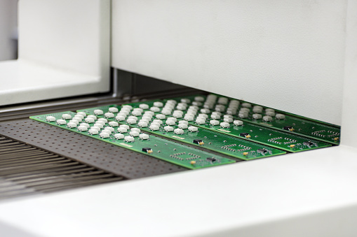 Electronic printed circuit board at the output of air convection reflow oven.  Manufacture of electronic components.