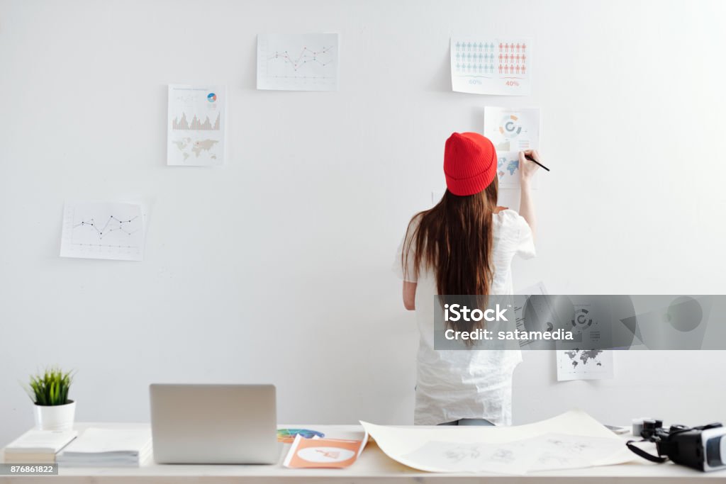 Woman working on infopraphic at home office Young woman working from home office on analytical reports Freelance Work Stock Photo