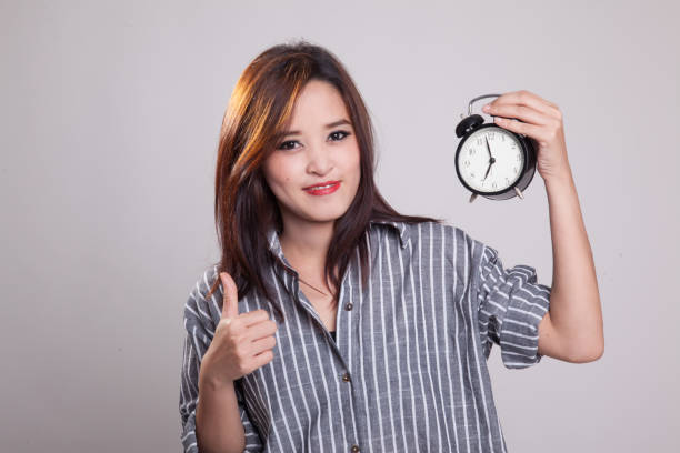 istock Young Asian woman show thumbs up with a clock. 876880246