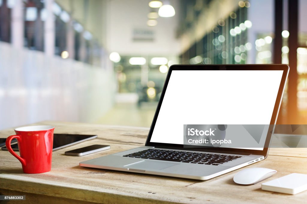 Laptop with blank white screen on table in office background Laptop Stock Photo