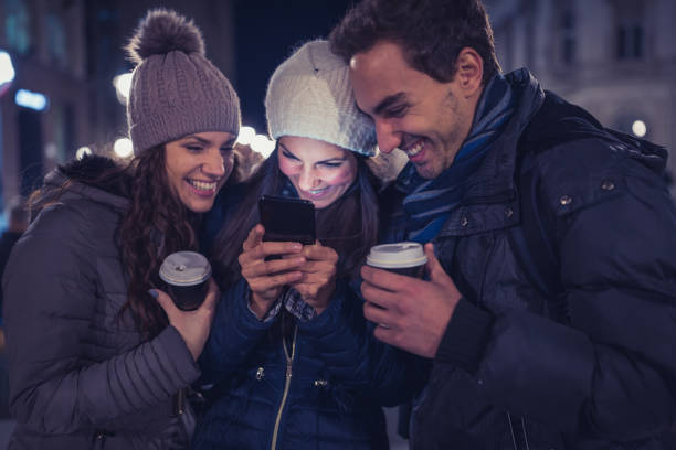 istock Young people having fun outdoors, watching social media posts on smart phone 876883504