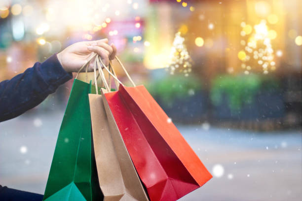 świąteczne zakupy - torby na zakupy w ręku z płatkiem śniegu na świątecznej dekoracji i oświetlenie na tle ulicy - christmas bag shopping bag gift zdjęcia i obrazy z banku zdjęć
