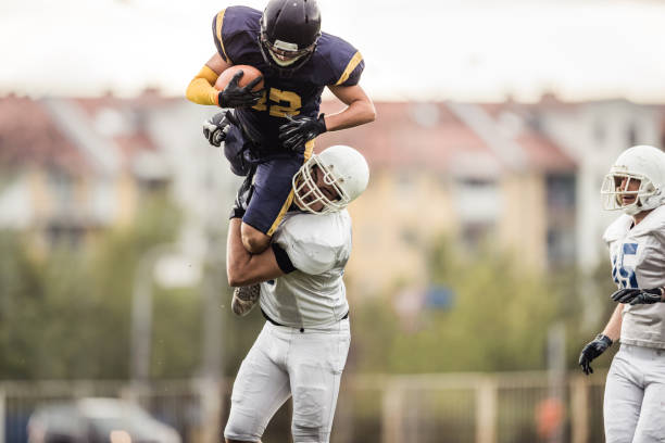 istock Determined American football player catching offense player during the game. 876884030