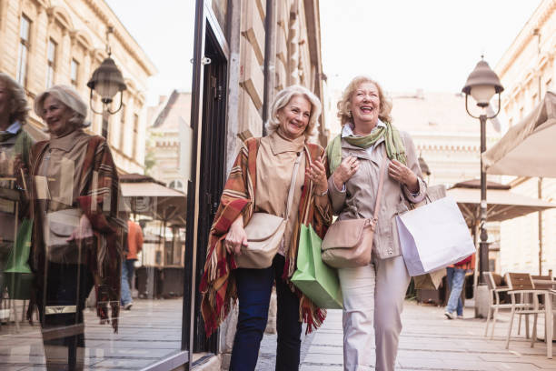 anziani sociali. donne anziane che fanno shopping, si divertono e ridono per strada - bag senior adult outdoors friendship foto e immagini stock