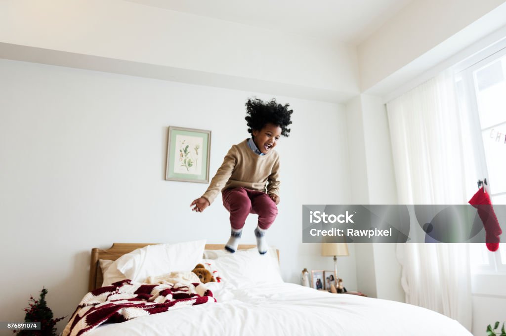 Africain kid amuser un temps sauter sur un lit - Photo de Sauter libre de droits