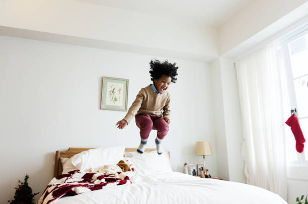 African kid having a fun time jumping on a bed