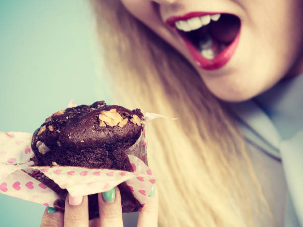 Sweet food sugar make us happy. Attractive blonde woman holds yummy chocolate cupcake in hand, open mouth, craving for cake.