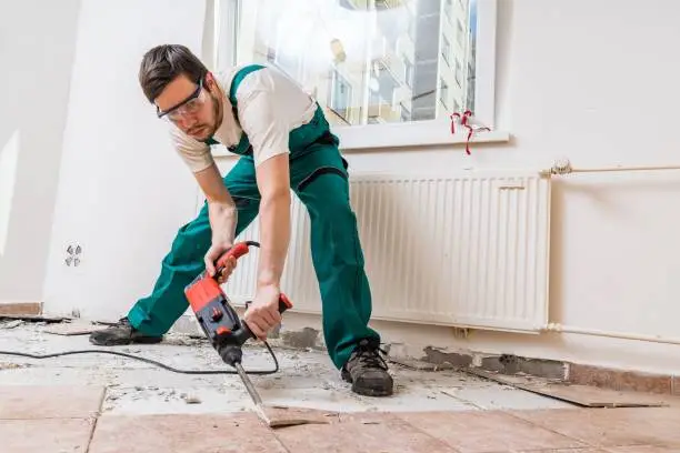 Photo of Demolition of old tiles with jackhammer. Renovation of old floor.