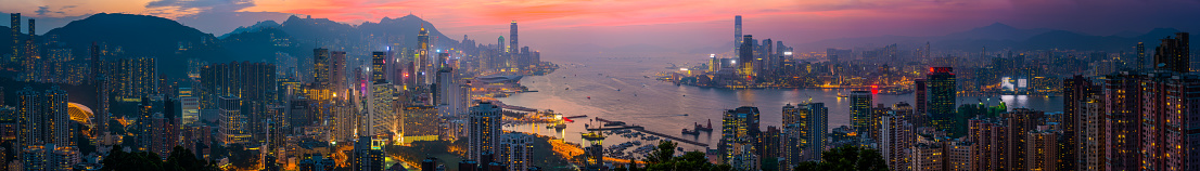 Sweeping panoramic vista over Victoria Harbour at sunset, from the glittering skyscrapers of Wan Chai, Admiralty and Central across the busy waterway to the crowded high-rises of Kowloon and Mong Kok in the heart of Hong Kong, China.