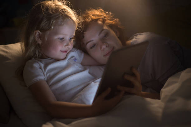 istock Cute Girl Reading E-Book with Mother 876919324
