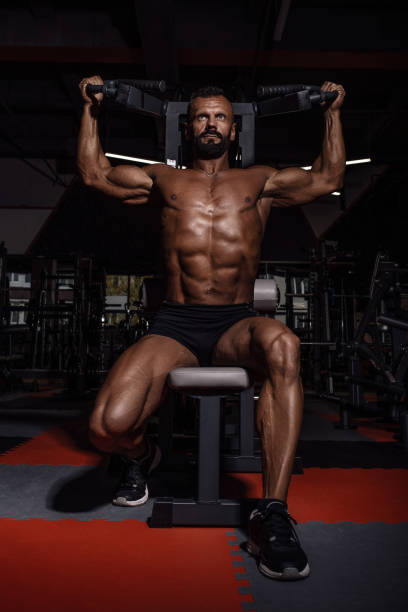 istock Handsome man with big muscles working out in gym. Muscular bodybuilder doing exercises. 876922878