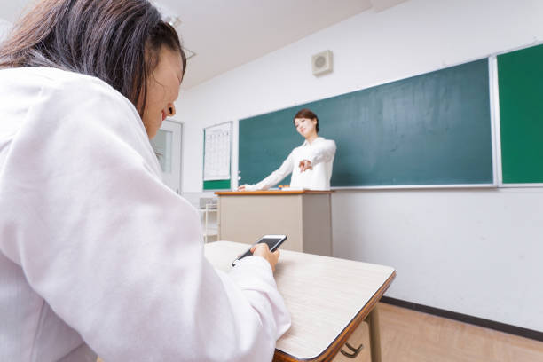 istock Teacher fuming at student for using smartphone during lesson 876924328