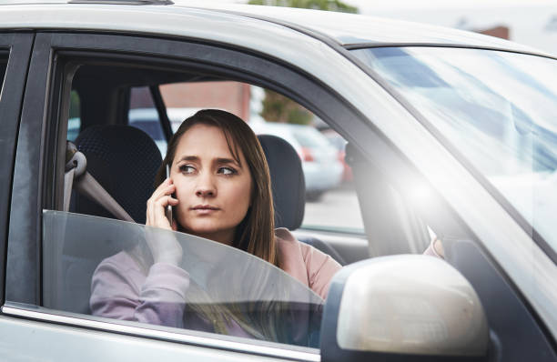 istock Woman driver talking on mobile phone turns, frowning 876924398