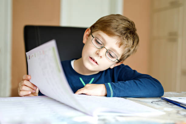 istock Happy school kid boy at home making homework 876927054