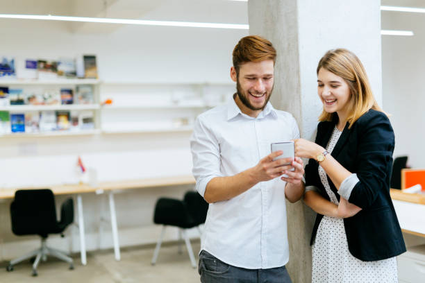 istock Couple smiling while looking the phone in office 876930940