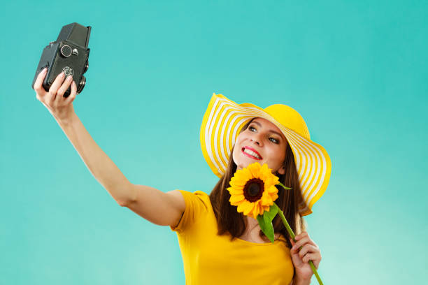 istock Summer woman holds sunflower old camera 876934196