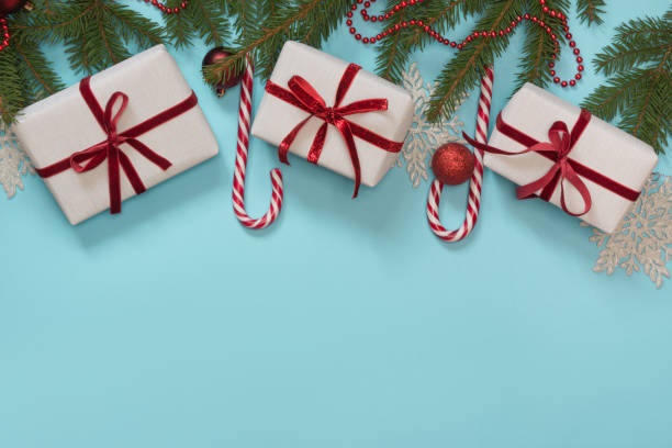 istock Christmas creative gift box wrapped with red ribbon, pack paper composed on blue. Flat lay. Top view. Creative hobby. 876934390