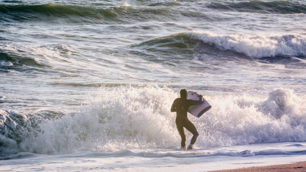 istock Beautiful surfer silhouette on the beach and sea waves 876935008