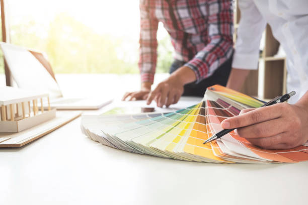 istock Two interior design or graphic designer at work on project of architecture drawing with work tools and color swatches, colour chart, color samples for selection, renovation and technology concept 876941014