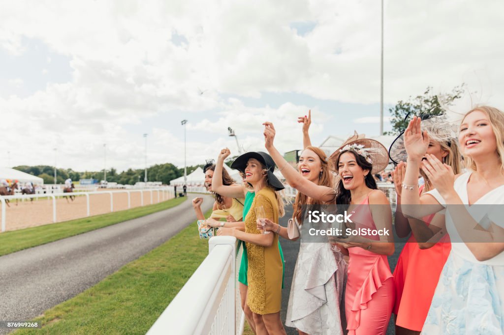 Horses Racing on Ladies Day A group of young women cheering on the horses as they race by on the track at ladies day. Horse Racing Stock Photo