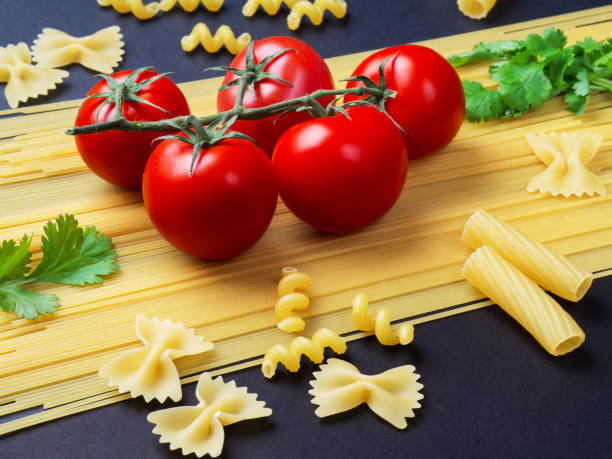 istock Spaghetti, tomatoes on a branch and parsley on a branch on a black background. 876957086