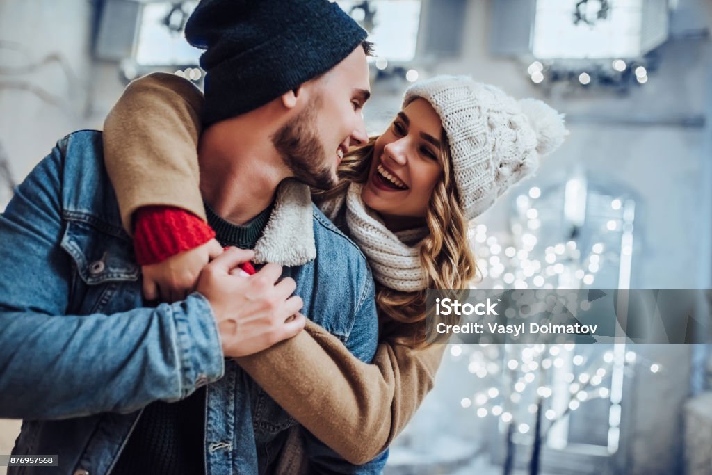 Young romantic couple is having fun outdoors in winter Young romantic couple is having fun outdoors in winter before Christmas. Enjoying spending time together in New Year Eve. Two lovers are hugging and kissing in Saint Valentine's Day. Winter Stock Photo