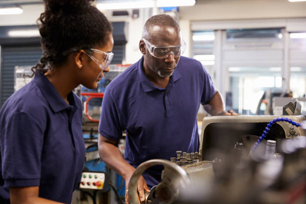 istock Engineer Showing Female Teenage Apprentice How To Use Lathe 876961820