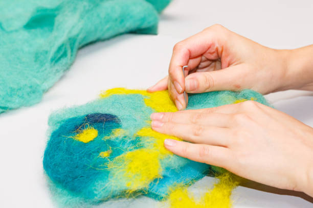 Female hands with a needle roll their wool in a dry way.
