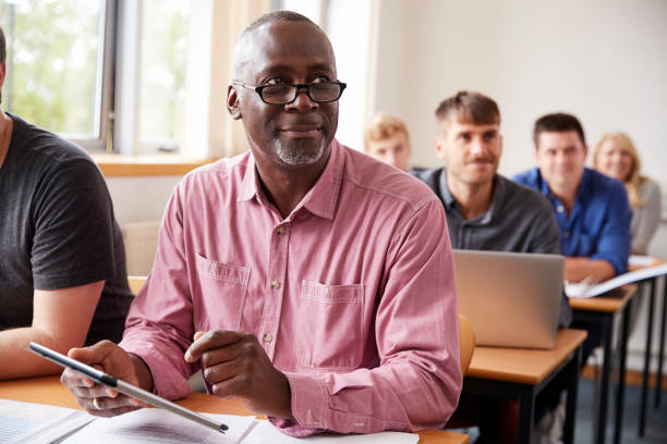 Mature Student Using Digital Tablet In Adult Education Class Mature Student Using Digital Tablet In Adult Education Class adult stock pictures, royalty-free photos & images