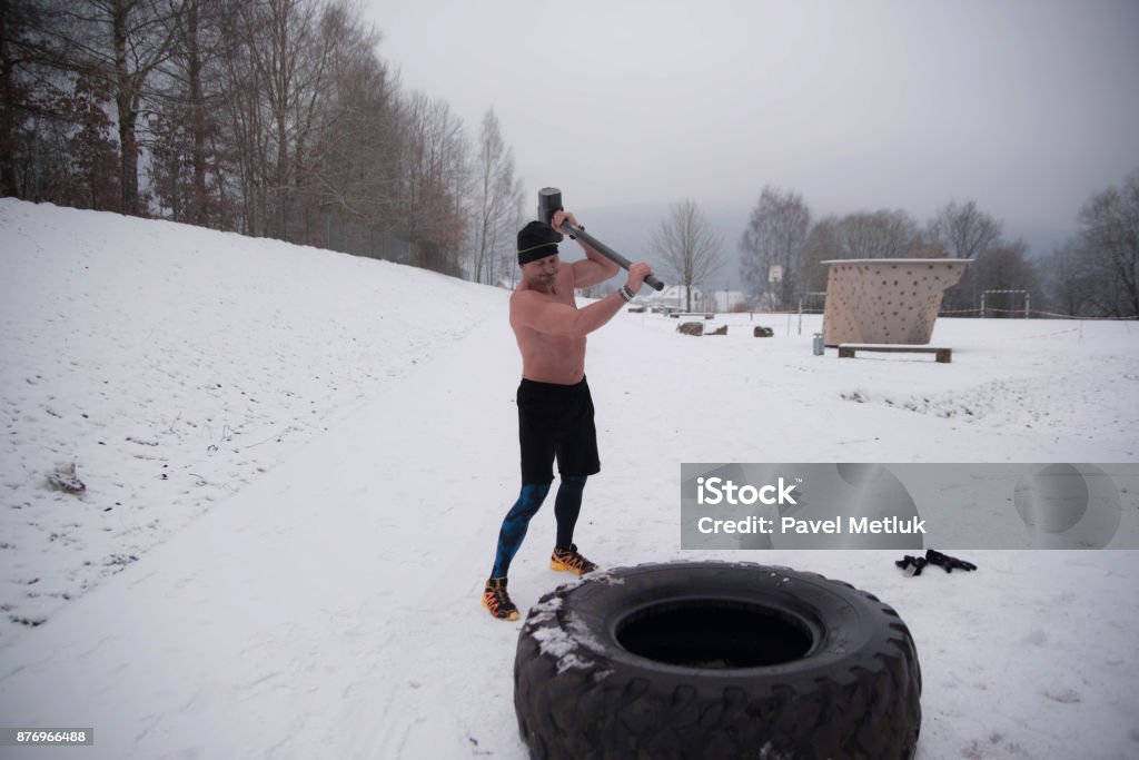 Sledgehammer Tire Hits men workout at gym with hammer and tractor tire Biceps Femoris Stock Photo
