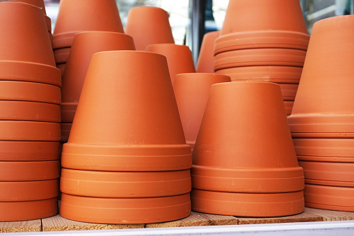 Many ceramic flower pots are standing on the shelf.