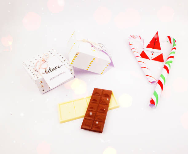 istock Christmas decoration with square gift box with dark and white chocolate and candy cane for celebration with snow and bokeh best Flat lay Christmas holidays background image 876970070