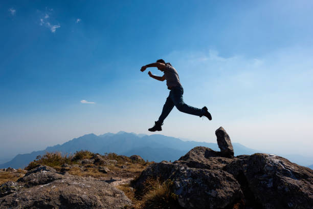 istock Men jumping with arms raised in a mountain top 876971248