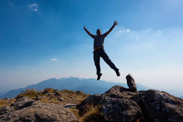 istock Men jumping with arms raised in a mountain top 876971270