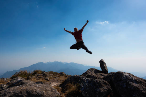 istock Men jumping with arms raised in a mountain top 876971282