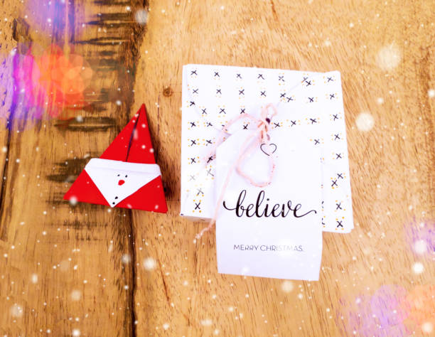 istock Christmas decoration on a wooden table with square gift box for celebration with snow falling and colorful bokeh best Christmas holidays background image 876971462