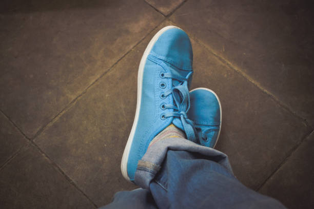 istock Feet jeans sneakers floor. Dark filter 876971550